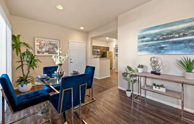 A dining room with a glass table and blue chairs.