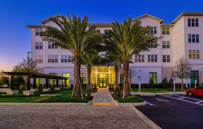 A hotel with a red car parked in front.