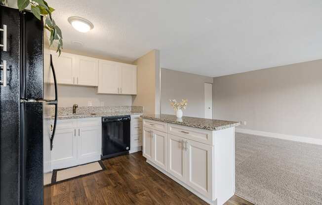 A kitchen with white cabinets and a black fridge.