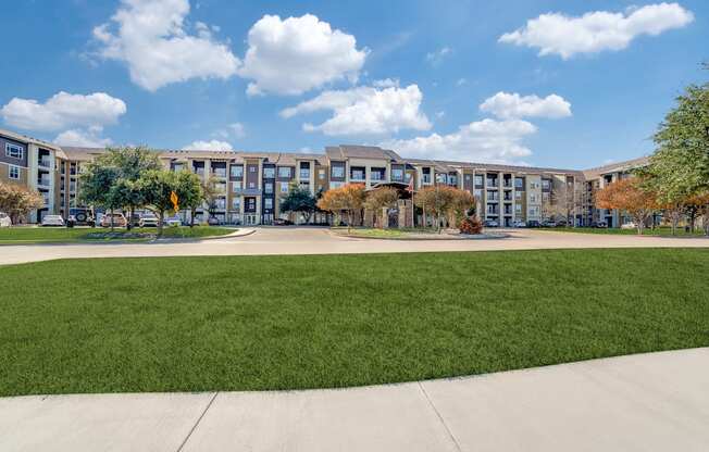 an exterior view of a large apartment building with grass and trees