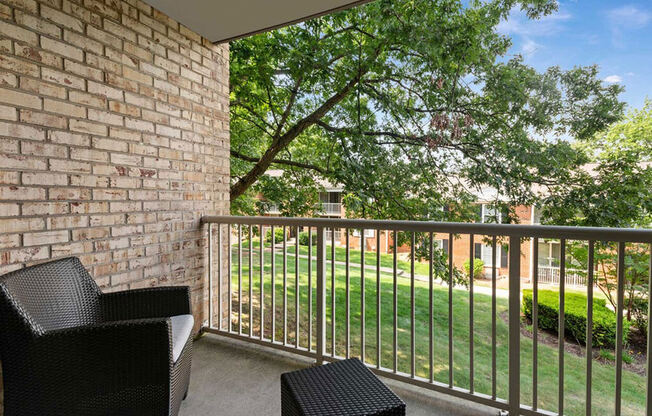 a balcony with two chairs and a tree in the yard