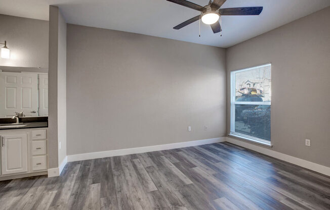 an empty room with a ceiling fan and a window