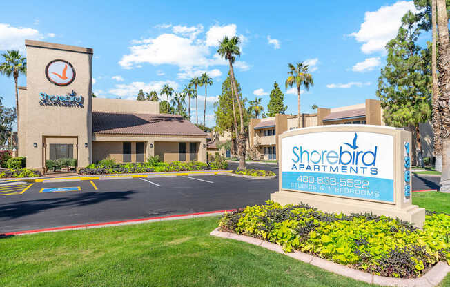 A sign for Shorebird Apartments is in front of a building with palm trees in the background.