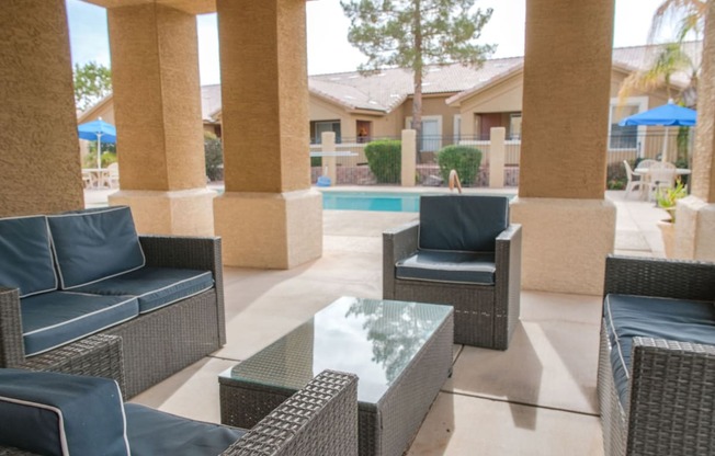 a patio with chairs and a table in front of a pool