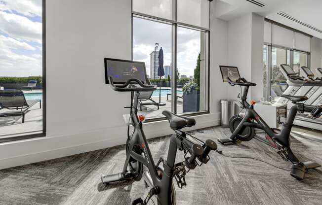 a gym with exercise bikes and a pool in the background
