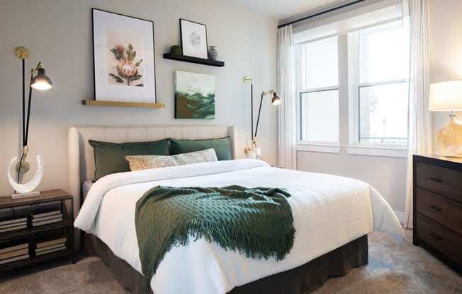 A bedroom with a large bed and a green throw blanket.