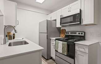 A modern kitchen with a stove, refrigerator, and microwave.