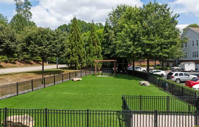 the yard is fenced off with a grass lawn and a swing set