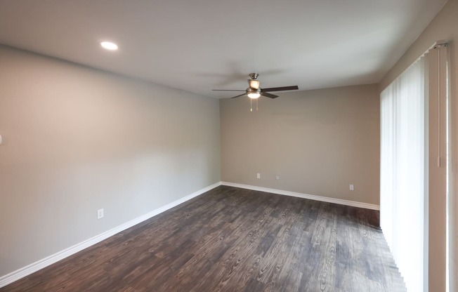 Living area view with wood look flooring, ceiling fan, and sliding glass door access to patio