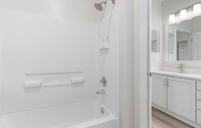 a white bathroom with a tub and a sink