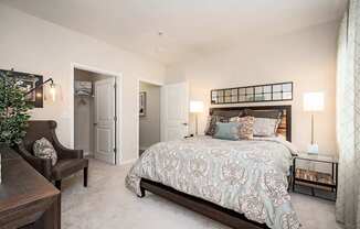 A bedroom with a large bed and a chair.