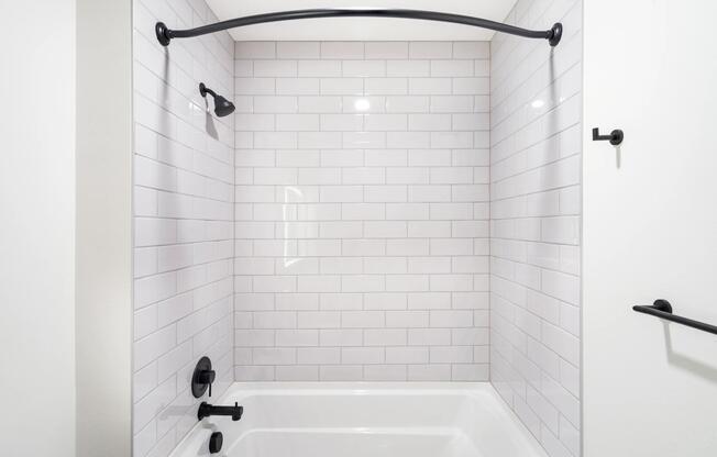 Bathroom with white tile surround, matte black fixtures, and a clean-lined tub and shower design suited to everyday comfort.