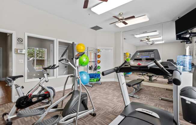 a gym with various exercise equipment in a room with a window