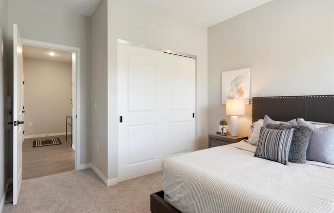 A bedroom with a large bed and a nightstand with a lamp.