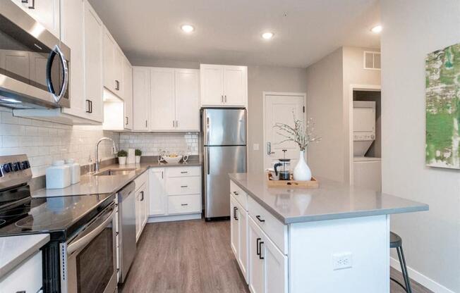 A modern kitchen with stainless steel appliances and white cabinets.