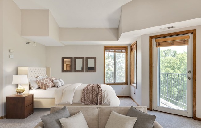 a bedroom with a bed and a couch and a door to a balcony