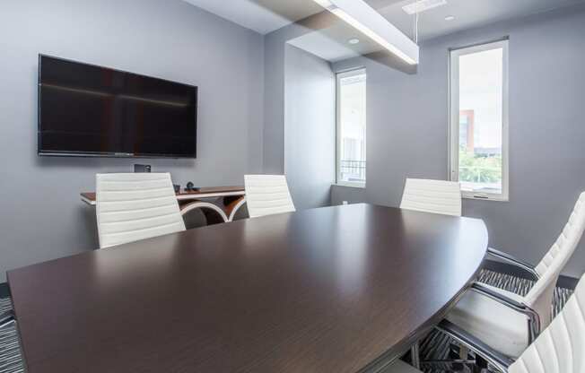 a conference room with a large table and chairs and a television