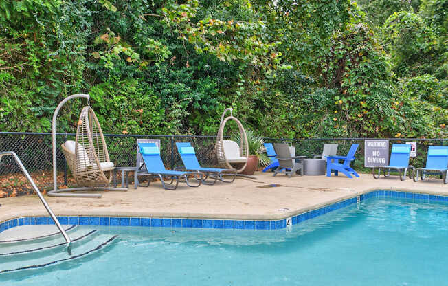 A pool surrounded by trees and chairs.at Lofts of Wilmington, Wilmington, North Carolina