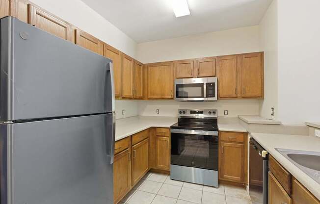 A kitchen with a refrigerator, microwave, oven, and sink.