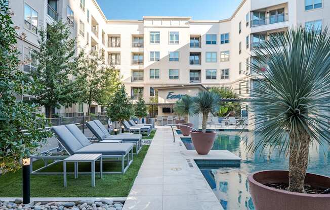 A pool surrounded by chairs and plants in front of a building.