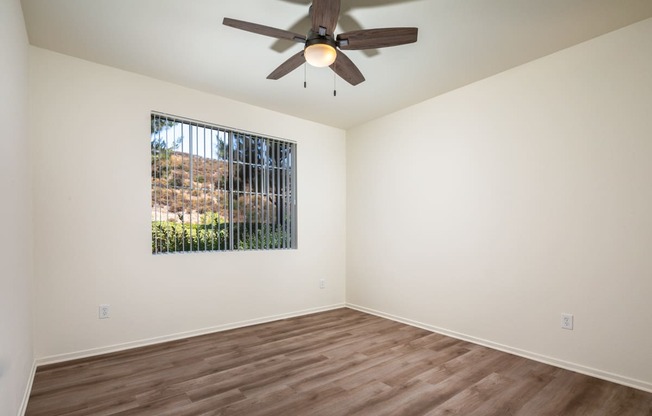 an empty living room with a ceiling fan and a window