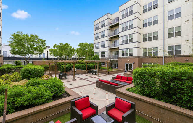 A courtyard with red and black chairs and a brick wall.