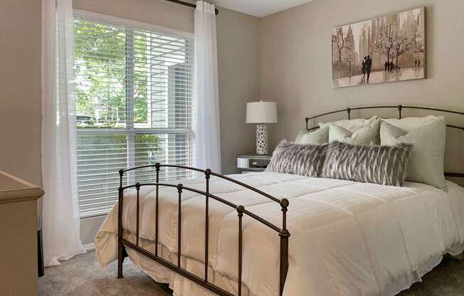 A bedroom with a large bed and a painting on the wall.