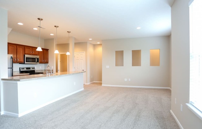 an empty living room and kitchen with a counter top