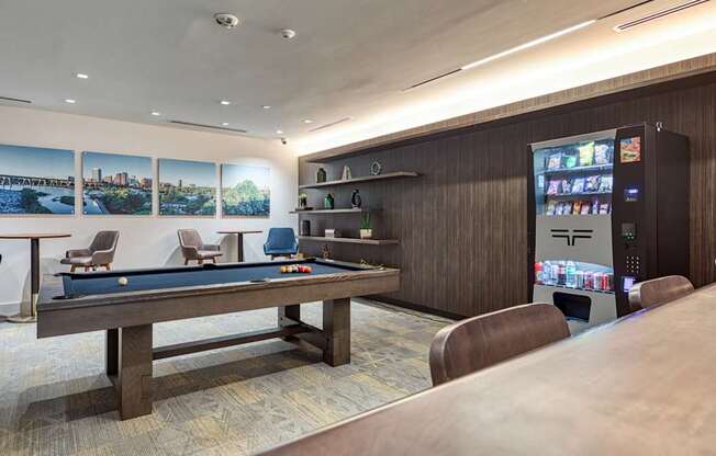 A room with a pool table, a vending machine, and a bar.