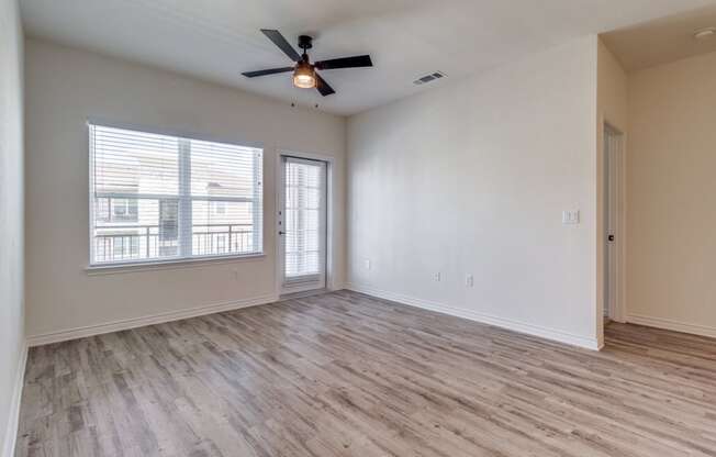 an empty living room with a ceiling fan and a window