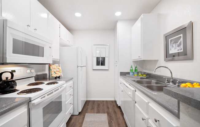 a white kitchen with stainless steel appliances and white cabinets