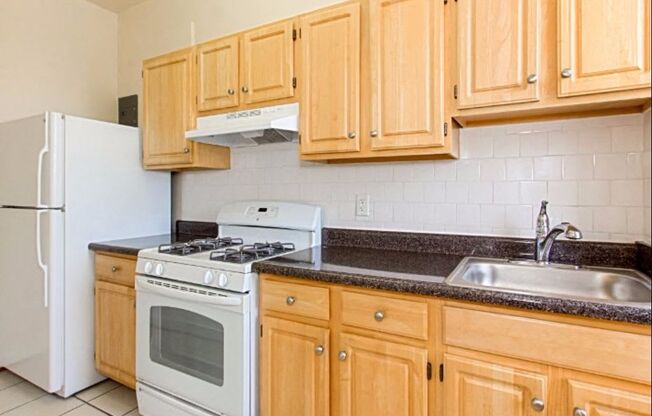 a kitchen with wooden cabinets and white appliances at the calverton apartments in washington dc
