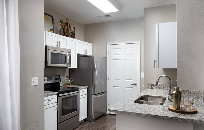 City Place at Westport - Modern Kitchen With Granite Countertops, Stainless Steel Appliances, and Wood Floors