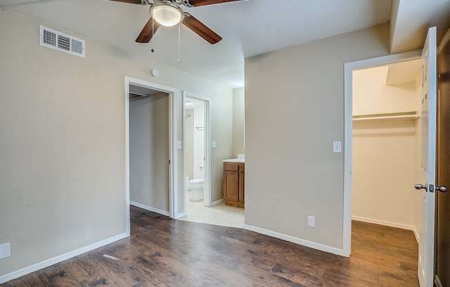 A room with a ceiling fan and a doorway leading to another room.