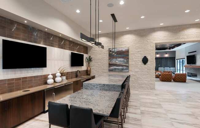 A modern kitchen with a long island and black chairs.