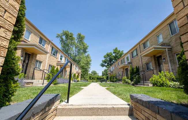 Ground-level perspective of landscaped courtyard and classic brick facades at Monon Court apartments, near Monon Trail access