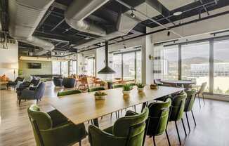 a large wooden table with green chairs and potted plants
