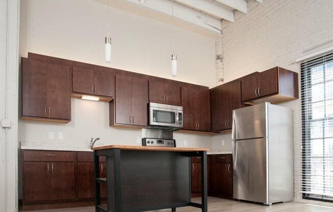 A kitchen with brown cabinets and a black island.