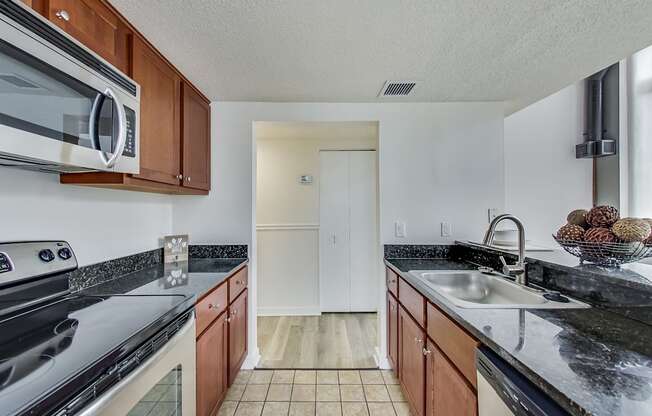 A kitchen with brown cabinets and black countertops at Lowertown Commons Apartments, St. Paul, MN