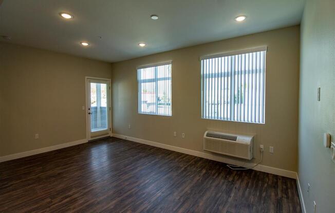 living room with hardwood floors and three windows at Loma Villas Apartments, San Bernardino, CA