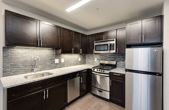 a kitchen with dark wood cabinets and stainless steel appliances