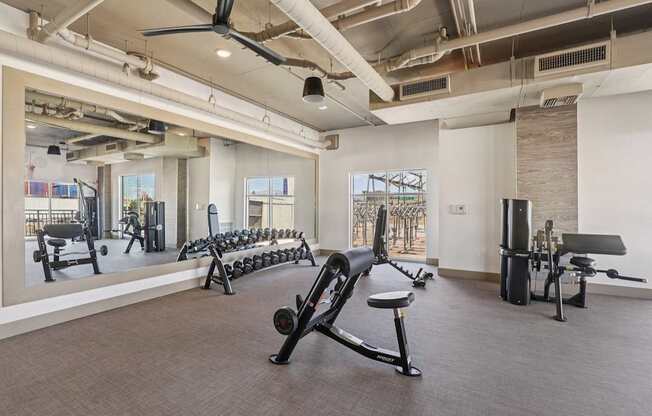 A gym with a variety of equipment including weights and a rowing machine.