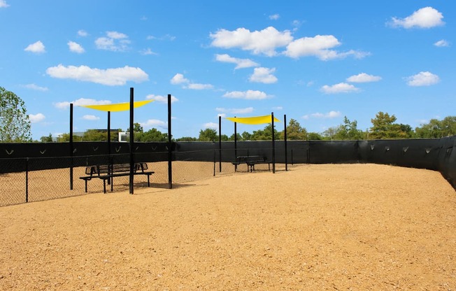 A sandy field with two yellow flags and a fence.