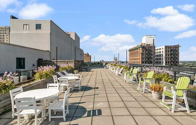 a roof terrace with tables and chairs and buildings in the background