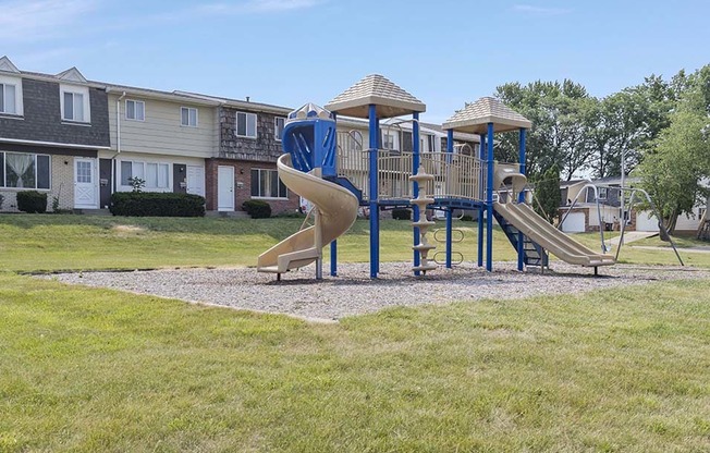 a playground with a slide in front of an apartment complex