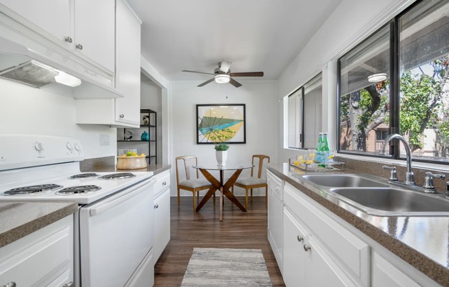 a kitchen with white cabinets and a sink and a window