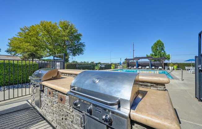 BBQ Picnic Area with Grills and View of Lounge Chairs and Pool at Silverstone Apartments, Davis, California