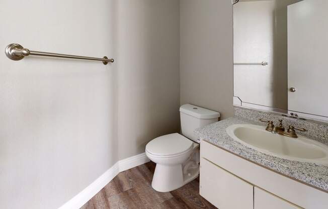 Apartments in Ontario - Rancho Vista - Bathroom With a Sleek Counter, a Sink With a Mirror, a Handtowel Rack, and a Toilet