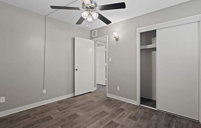 A room with a ceiling fan and wooden flooring.