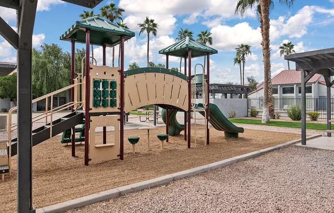A playground with a green slide and a brown and tan play structure.